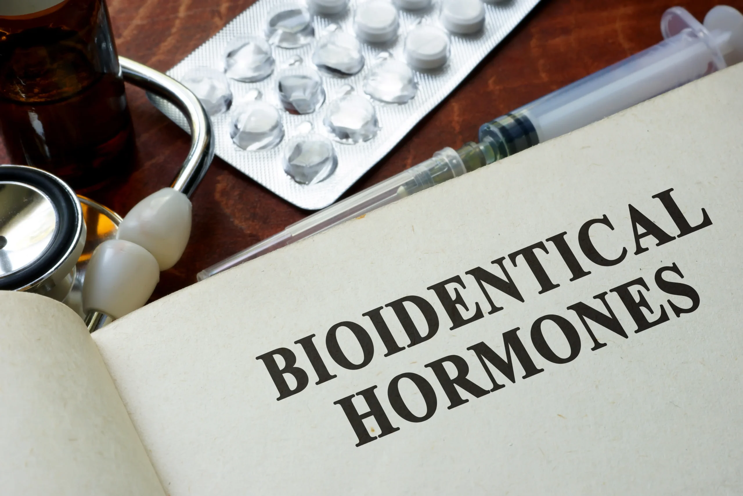 Open book displaying bioidentical hormones text beside medical supplies