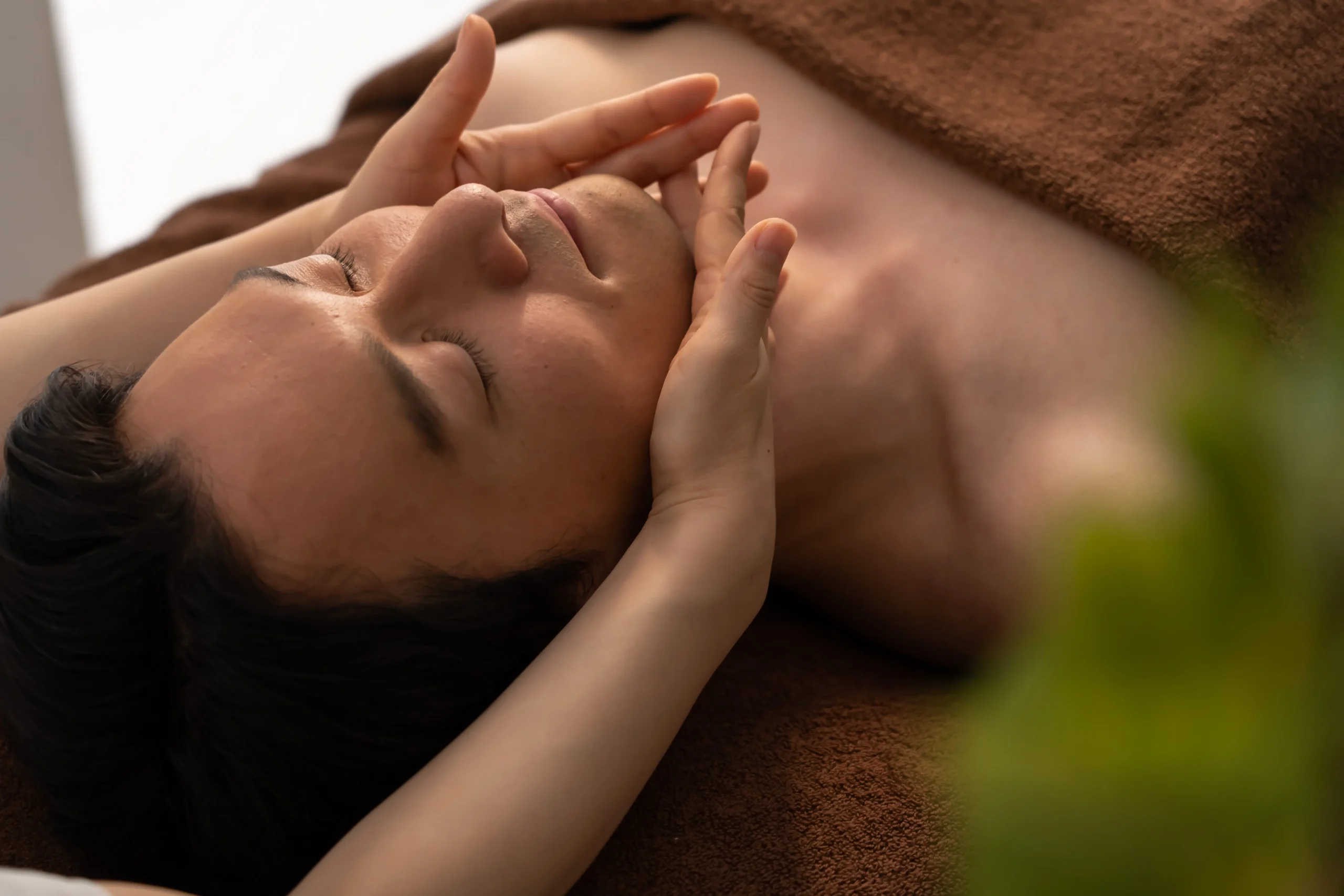 Man receiving facial massage treatment while lying on spa treatment bed