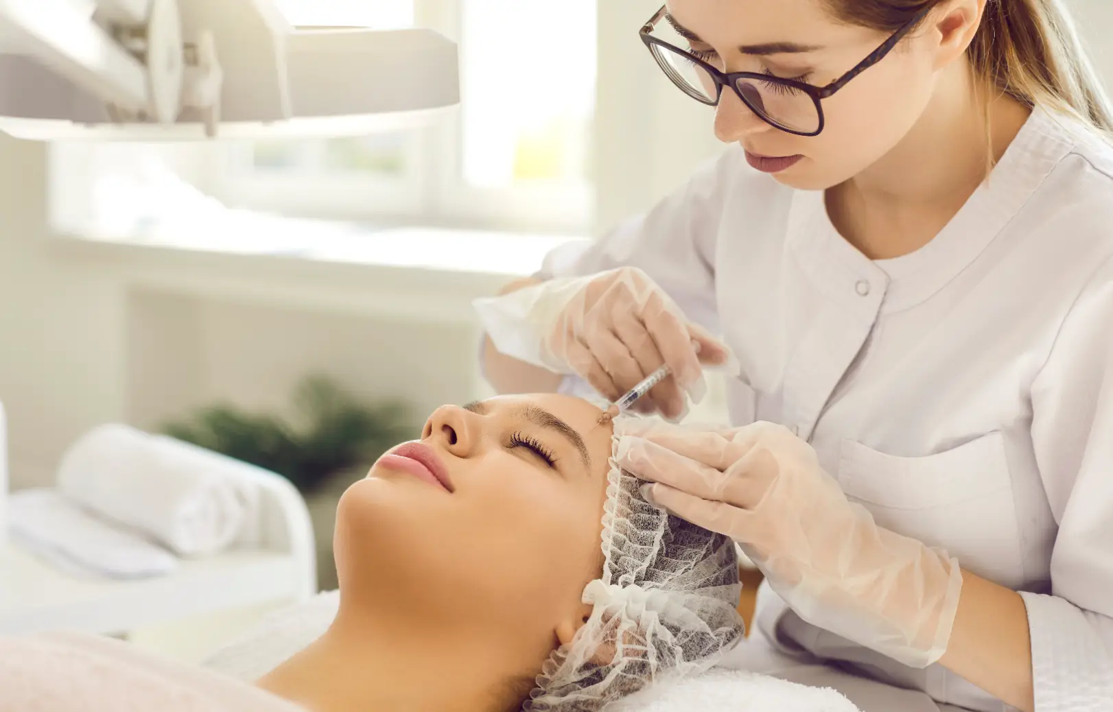 Practitioner administering an injection near the forehead of a reclining patient.